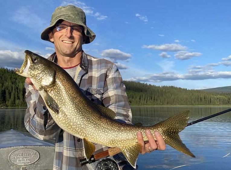 Man wearing bucket hat shows off large fish for camera.